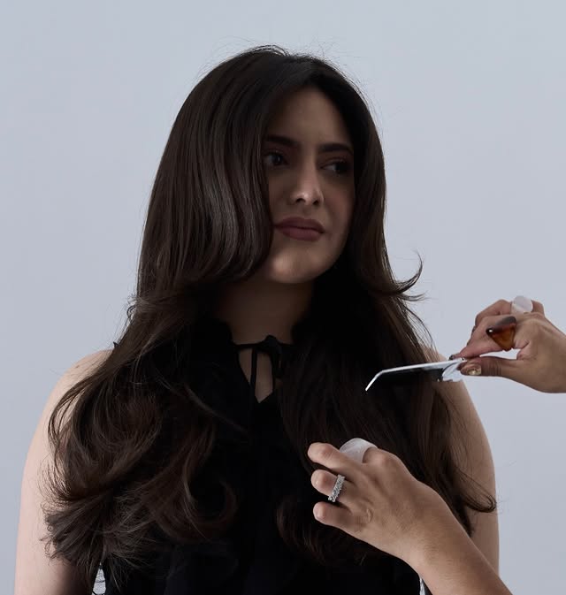 Cabello largo con reflejos cálidos sobre un fondo rosa suave